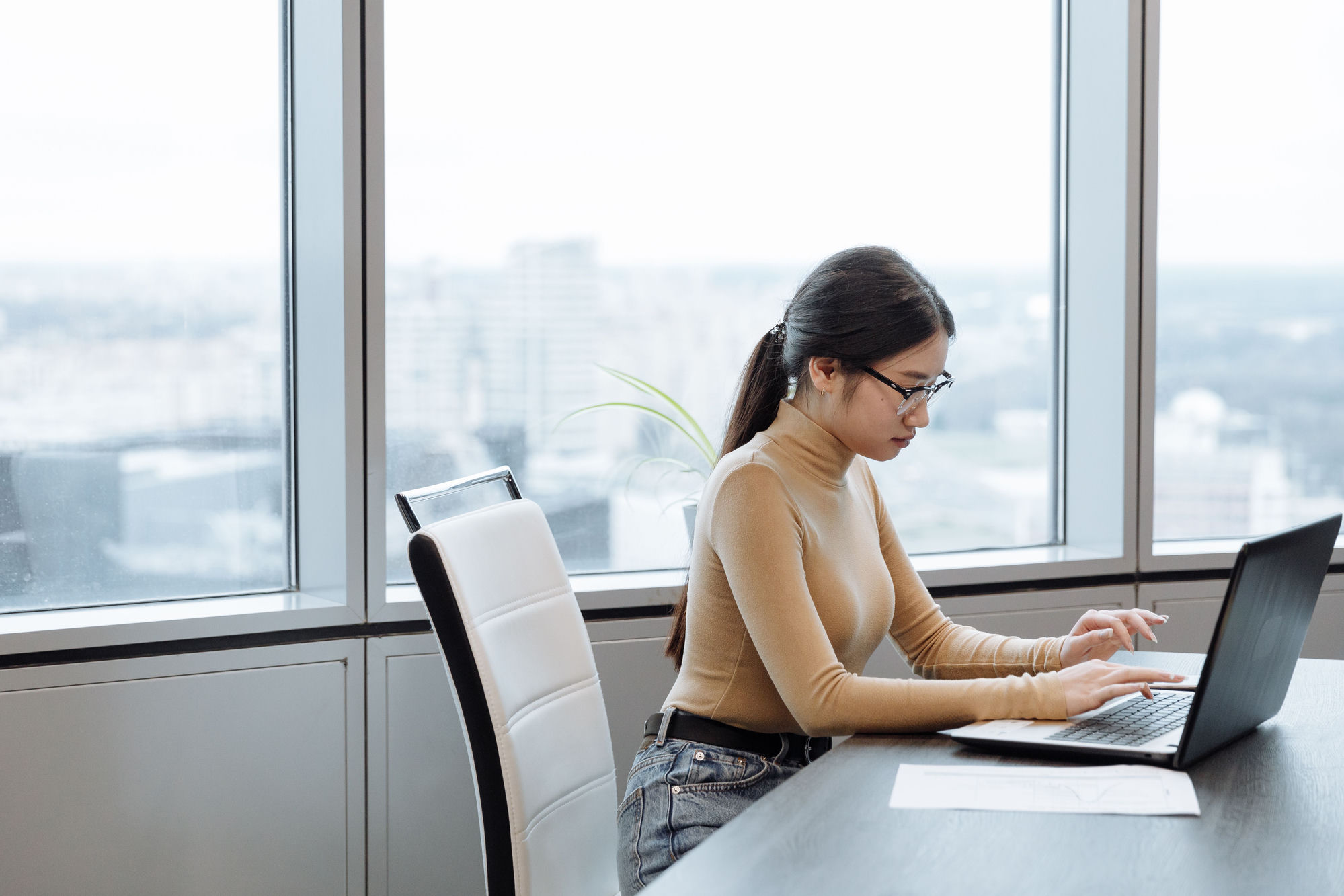 A clinician working at a laptop by a window