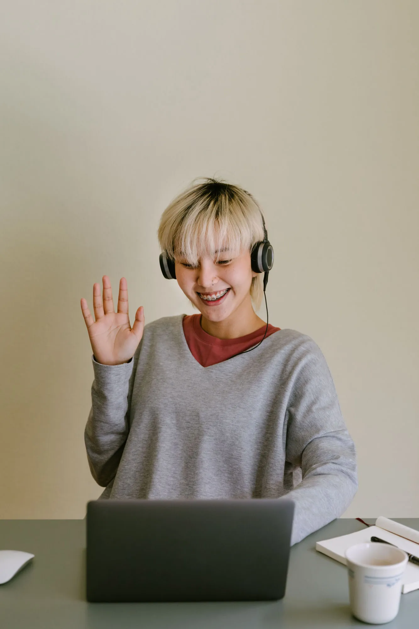A young person on a video therapy session, smiling and waving